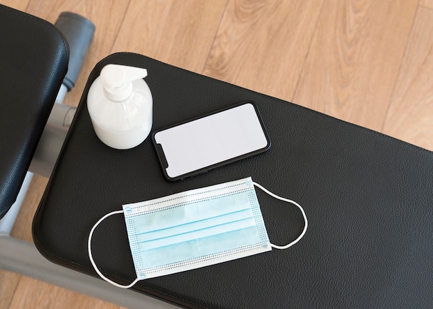 Top view of gym equipment with medical mask and hand sanitizer