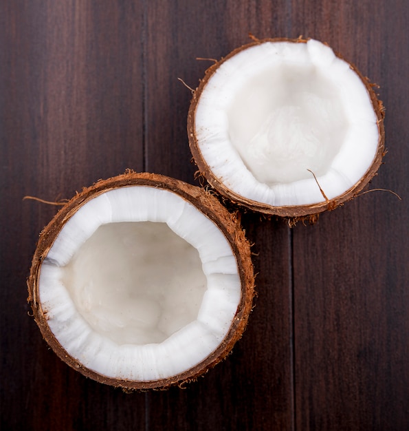 Top view of half brown and fresh coconuts on a wooden surface