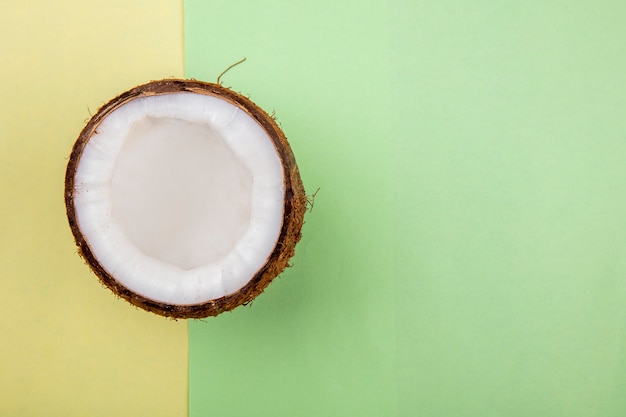 Vista dall'alto di mezza noce di cocco sulla superficie gialla e verde