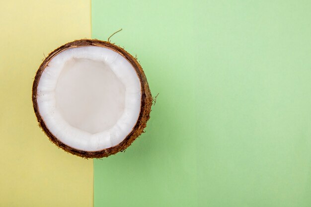 Top view of half coconut on yellow and green surface