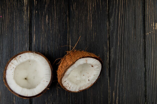 Top view of half cut coconut on wooden background with copy space