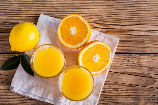 Top view half cut oranges and glasses with juice