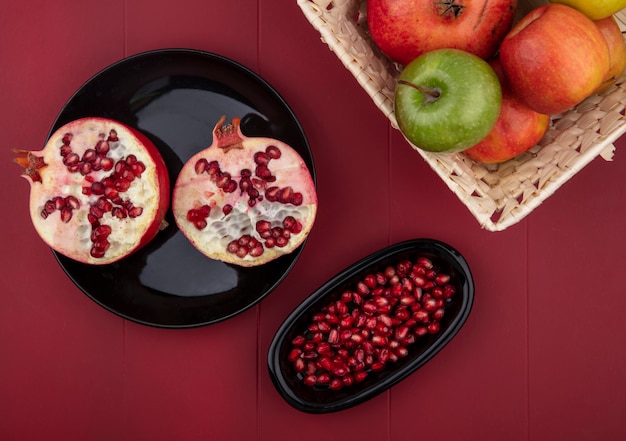 赤い表面に丸ごと1つのバスケットとリンゴとバスケットでザクロとザクロの果実を半分カットの平面図