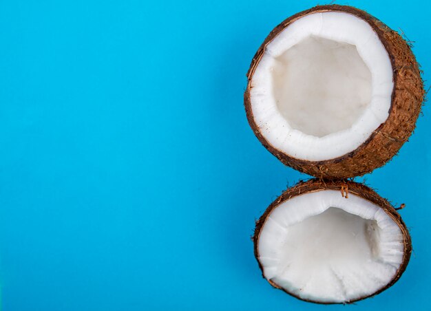 Top view of half of fresh big coconuts on blue surface