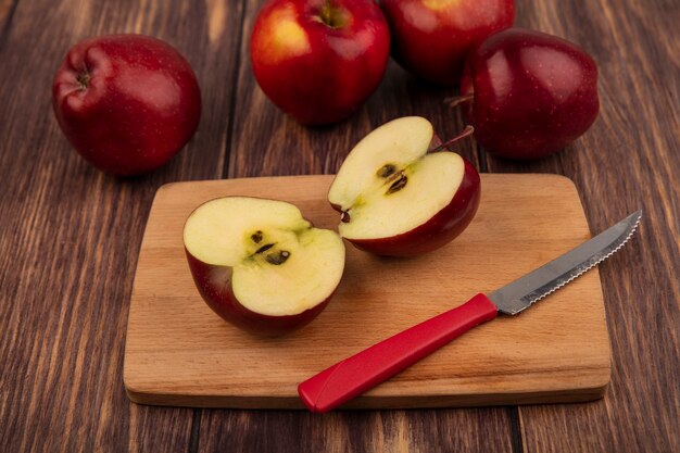 Top view of half red apples on a wooden kitchen board with knife with apples isolated on a wooden background