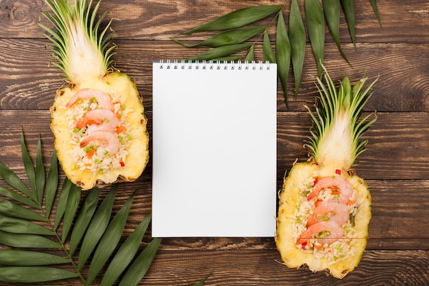 Top view halves of pineapple with notepad