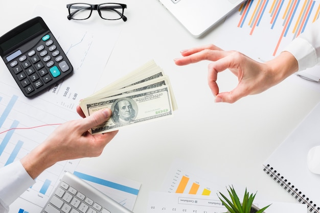 Top view of hand accepting money over desk