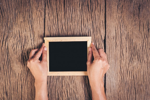 Top view Hand holding chalkboard  on wood background