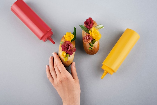 Free photo top view hand holding eco hot dog with flowers