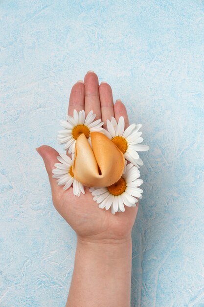 Top view hand holding fortune cookie with flowers