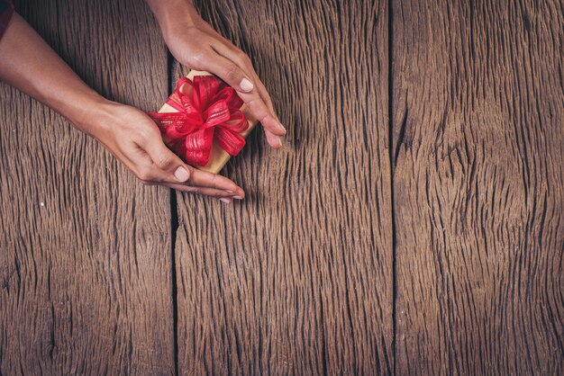 Top view hand holding gift box on wood background