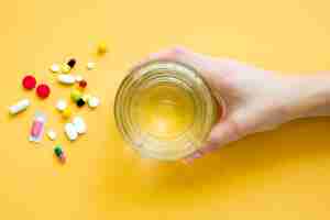 Free photo top view of hand holding glass of water with pills