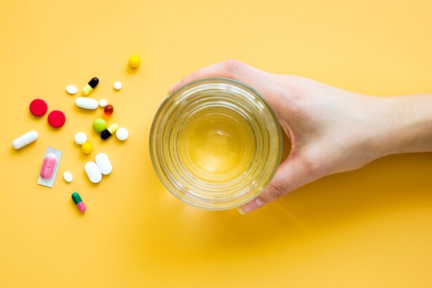 Top view of hand holding glass of water with pills