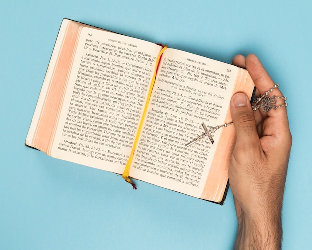 Free photo top view hand holding holy book and necklace