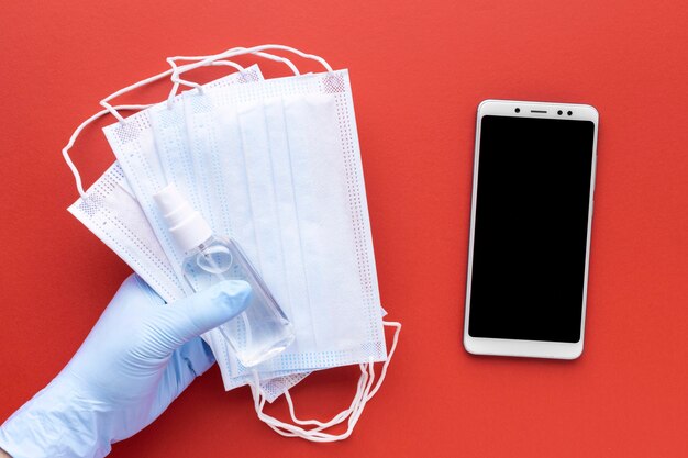 Top view of hand holding medical masks with smartphone