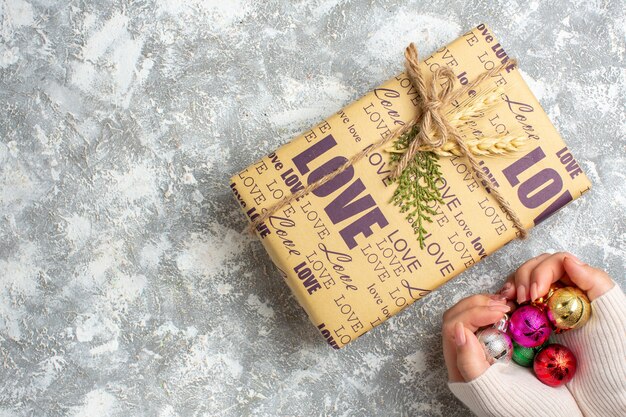 Top view of hand holding new year decoration accessories and gift on the left side on ice surface