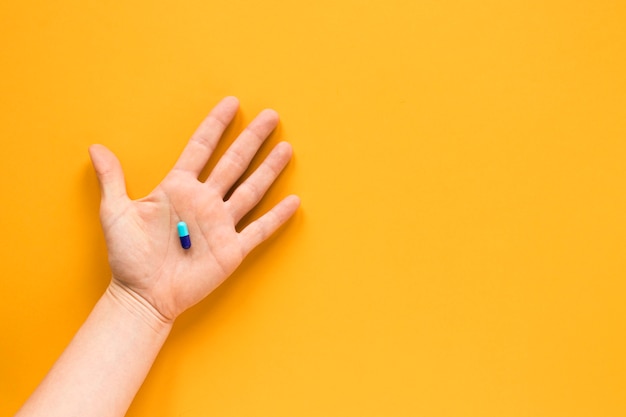 Free photo top view hand holding a pill with copy space