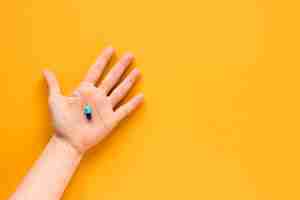 Free photo top view hand holding a pill with copy space