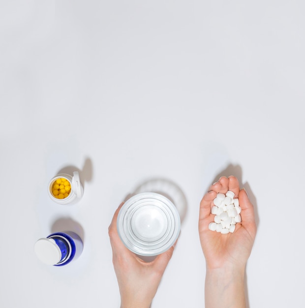 Top view of hand holding pills and glass of water