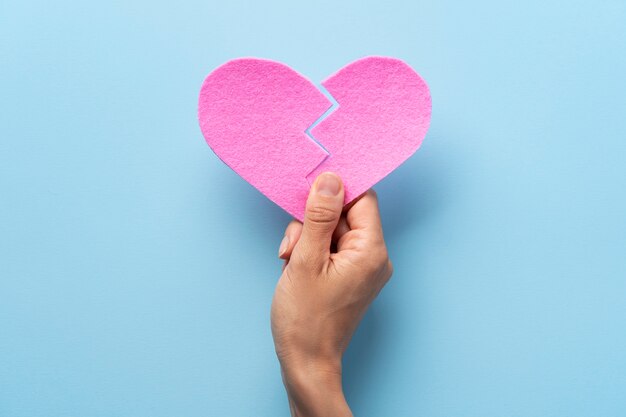 Free photo top view hand holding pink broken heart