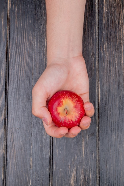 Free photo top view of hand holding red apple on wooden table