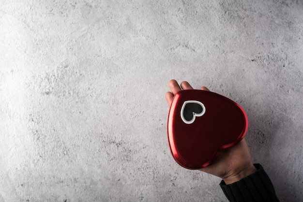 Top view Hand holding Red heart on wall background