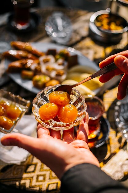 Top view of a hand holding a small glass saucer with apricot jam