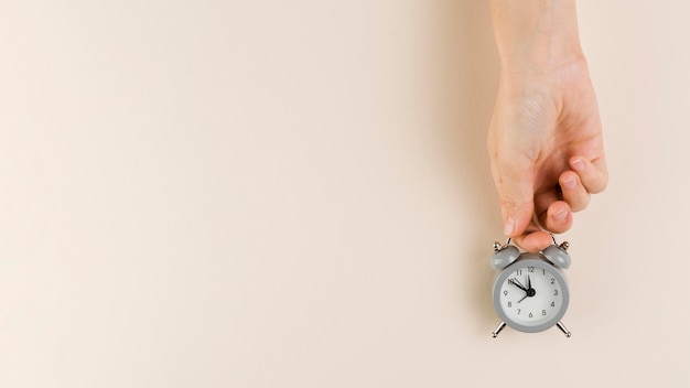 Top view of hand holding tiny clock with copy space