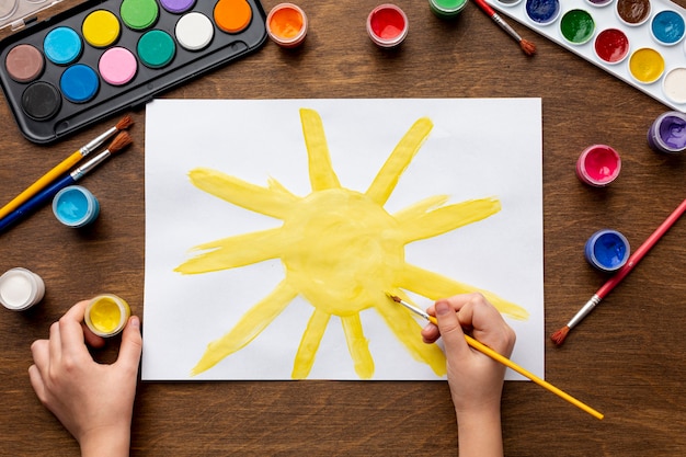 Top view of hand painting a sun