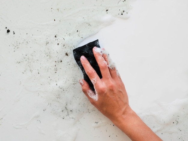 Top view of hand scrubbing dirt with sponge