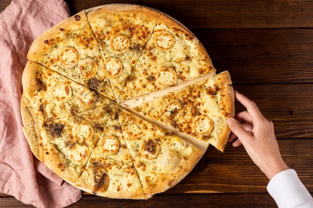 Top view hand taking slice of pizza with cheese