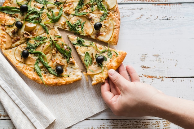 Top view hand taking slice of pizza