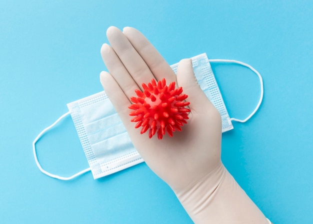 Foto gratuita vista dall'alto della mano con il guanto che tiene il virus con mascherina medica