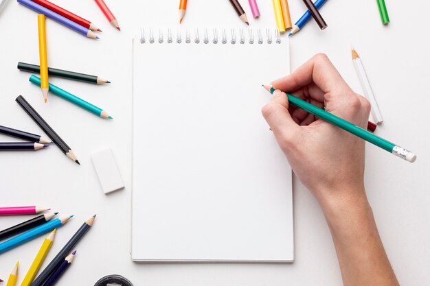 Top view of hand with pencil on notebook