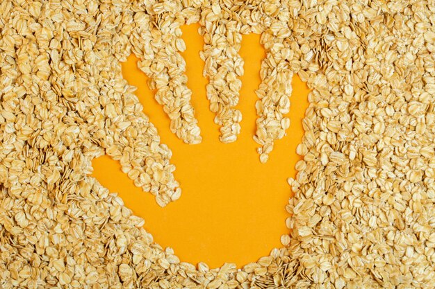 Top view of handprint on oat flakes on yellow