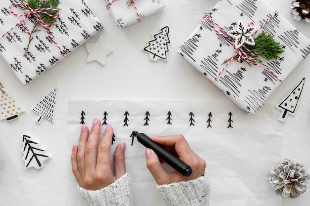 Foto gratuita vista dall'alto delle mani che disegnano alberi di natale per i regali