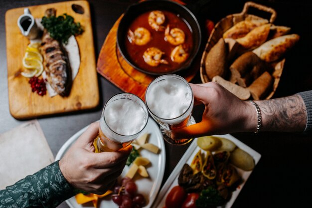 Top view of hands holding beer glasses pub surface