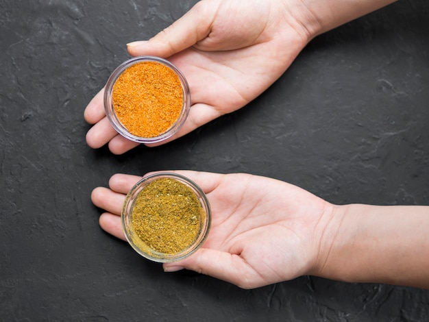 Top view hands holding bowls full of spices