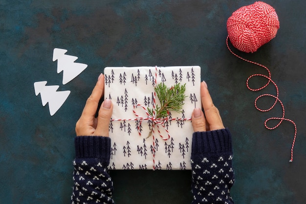Top view of hands holding christmas gift with string and plant