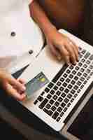 Free photo top view hands holding a credit card and a laptop