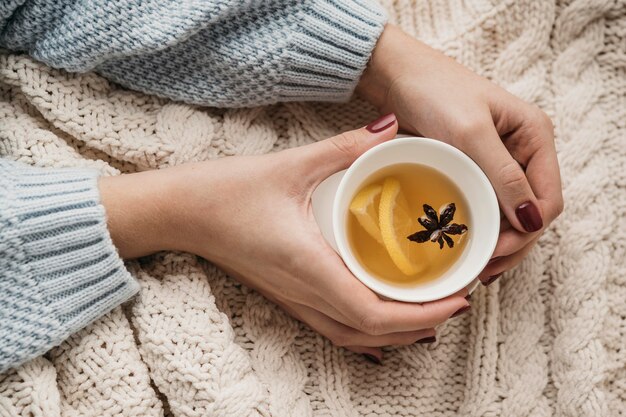 top view hands holding cup with tea and star anise