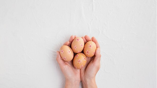 Вид сверху рук, держащих украшенные пасхальные яйца