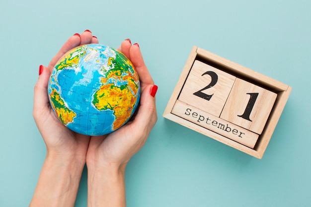 Top view of hands holding earth globe with calendar