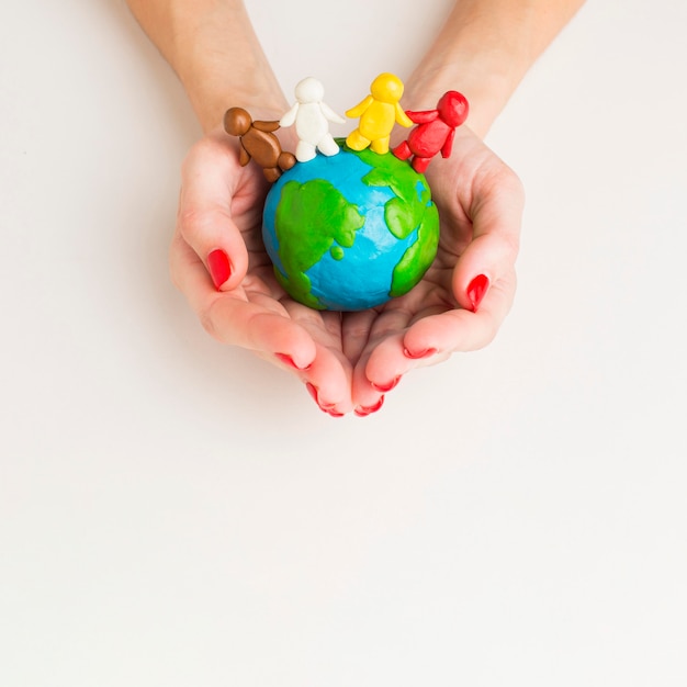 Top view of hands holding globe with people figurines