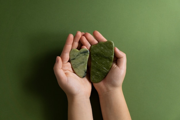 Top view hands holding green gua sha