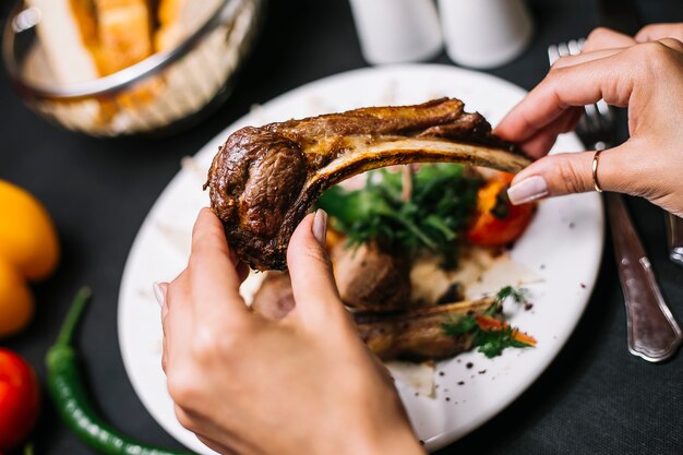 Top view of hands holding lamb rib kebab