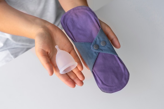 Free photo top view hands holding  menstrual products