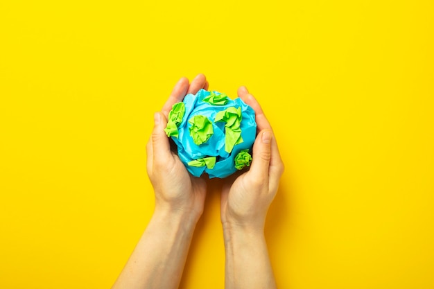 Top view hands holding planet on yellow background