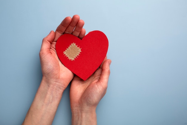 Top view hands holding red heart with patch