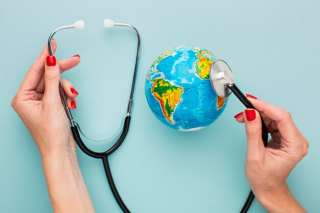 Top view of hands holding stethoscope with globe